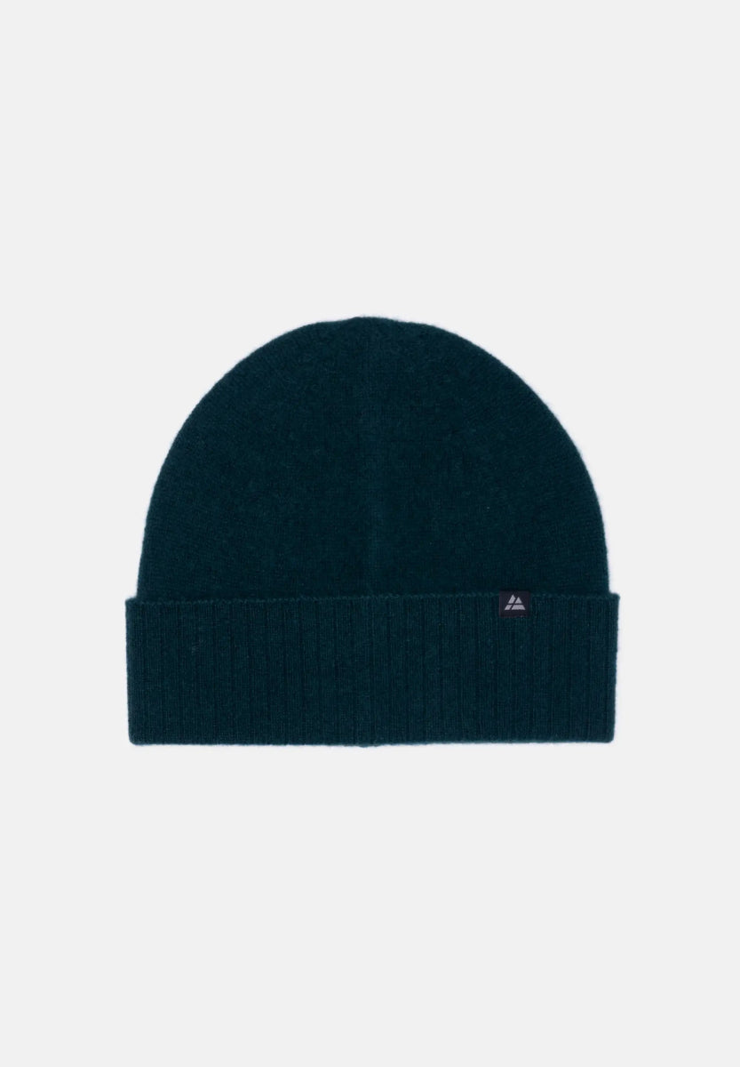 Dark blue cashmere beanie with folded brim and small logo tag on light background.
