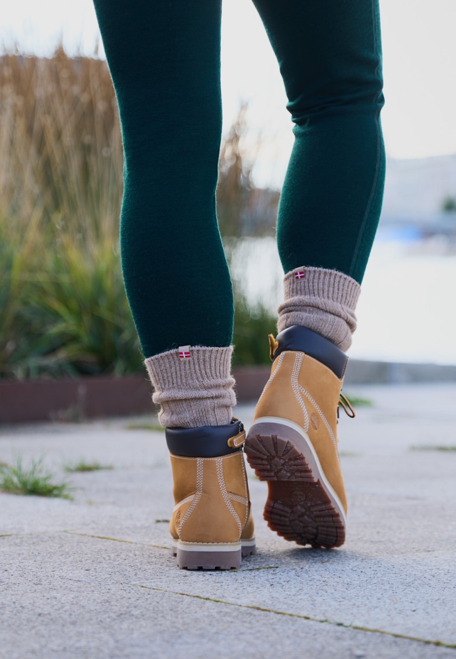 Tan alpaca wool socks with flag detail, worn with tan boots and green leggings, outdoors.