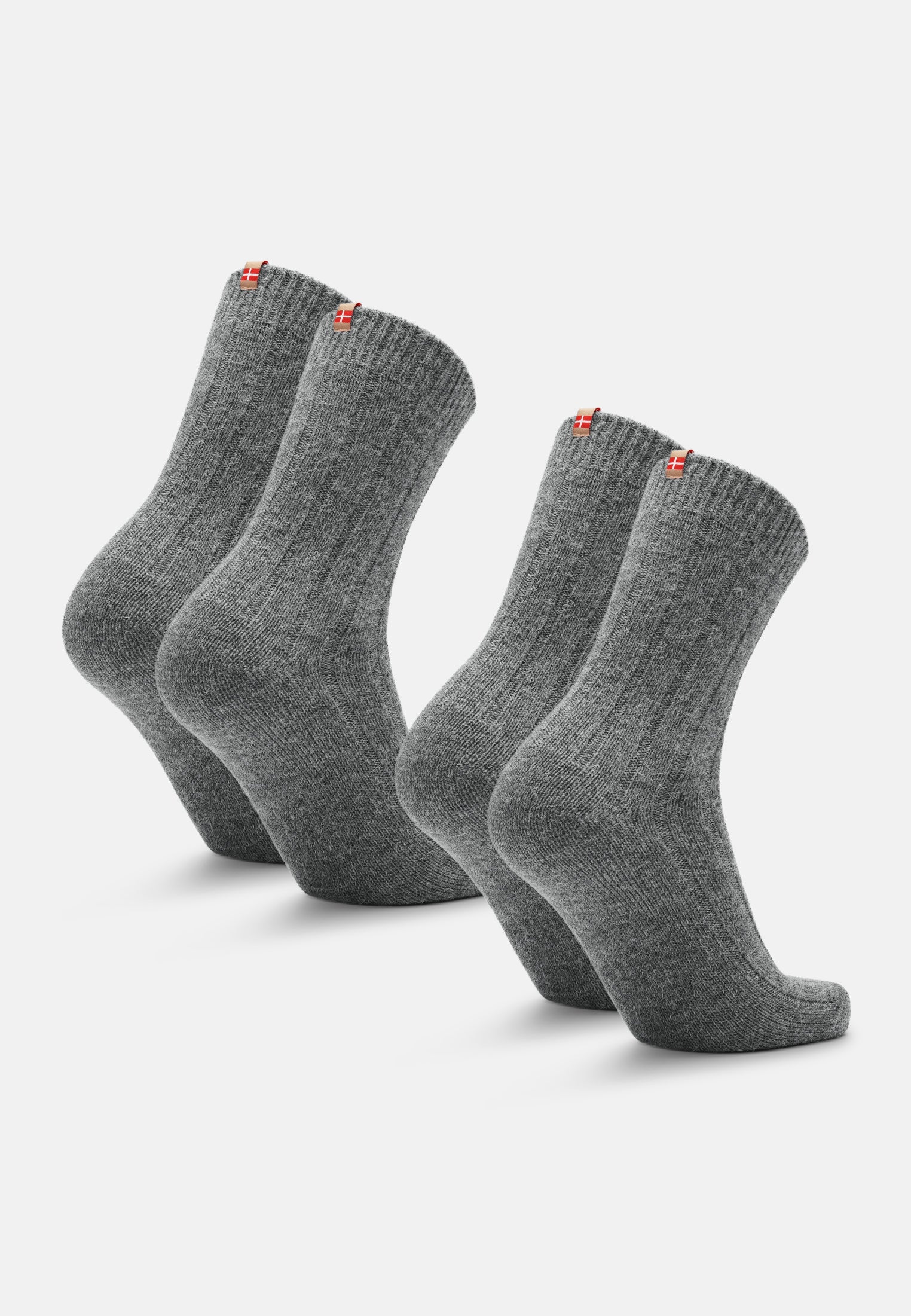 Four gray alpaca wool socks with red and white tags, standing upright on a plain background.