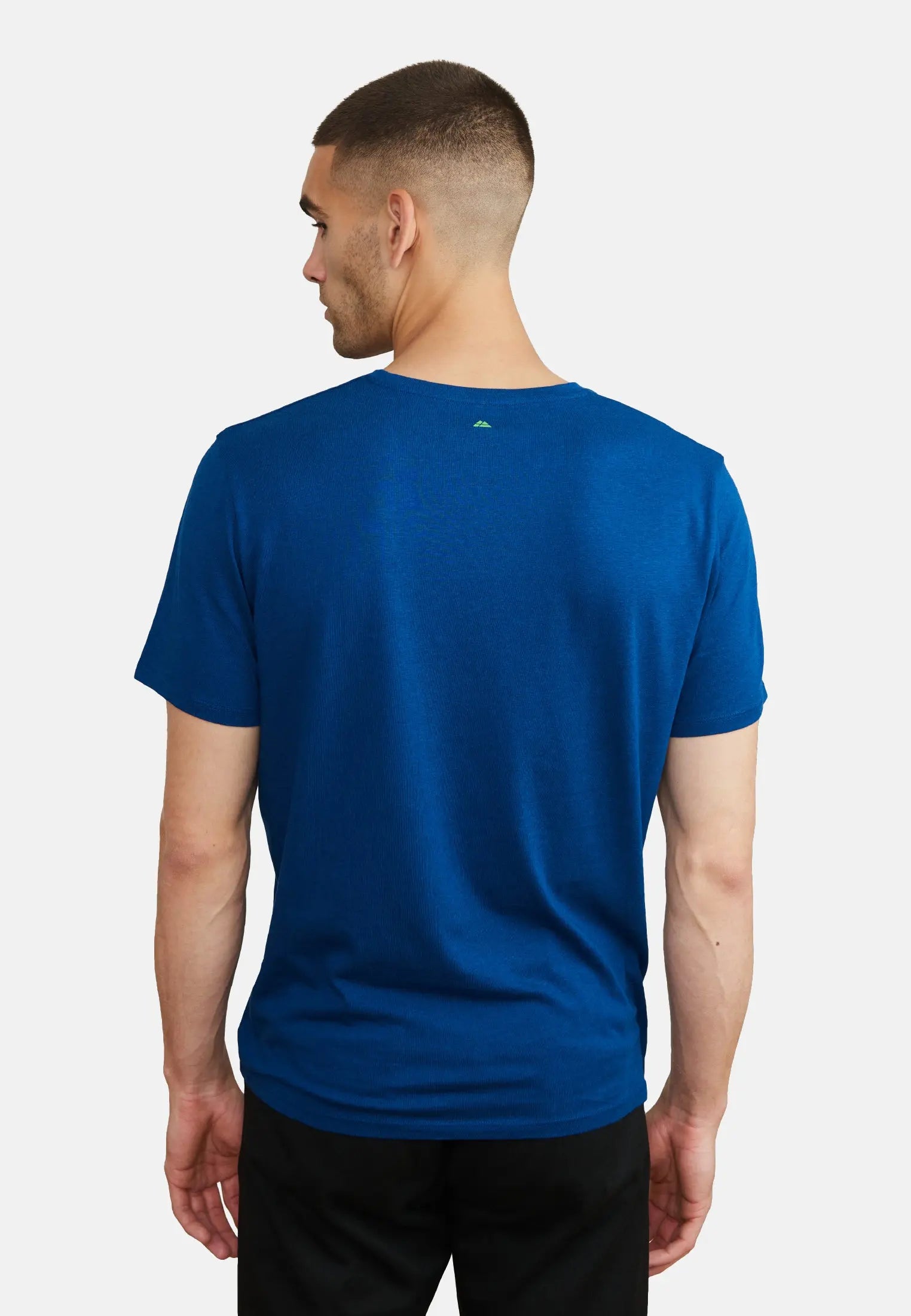 Man wearing a blue V-neck T-shirt and black pants, viewed from the back.