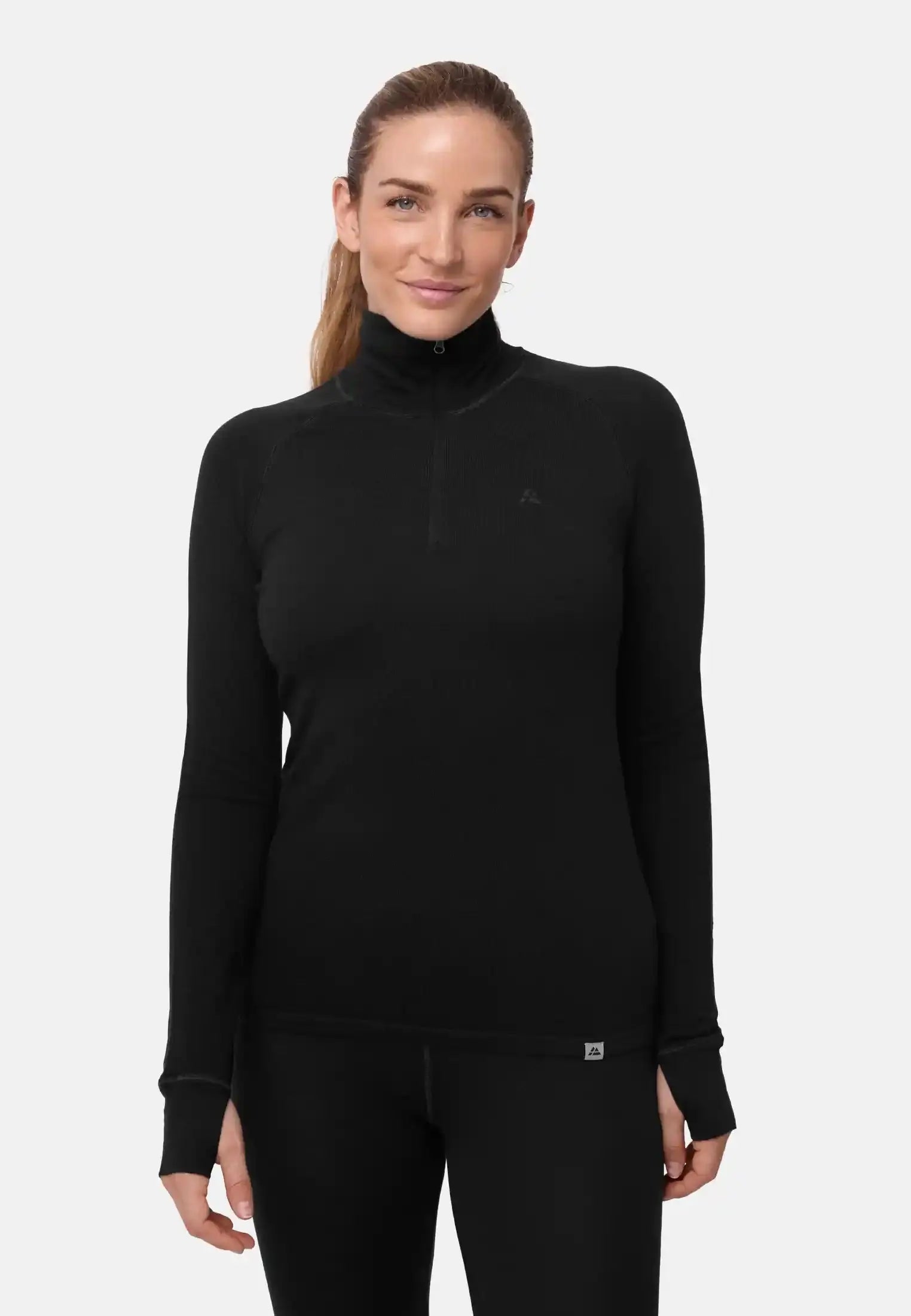 Woman wearing a black merino wool half-zip shirt, standing against a plain background.