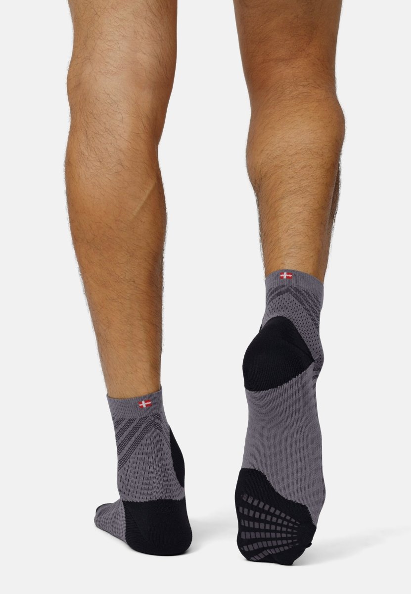 Legs wearing gray anti-slip running socks with black soles and a small flag design near the top.