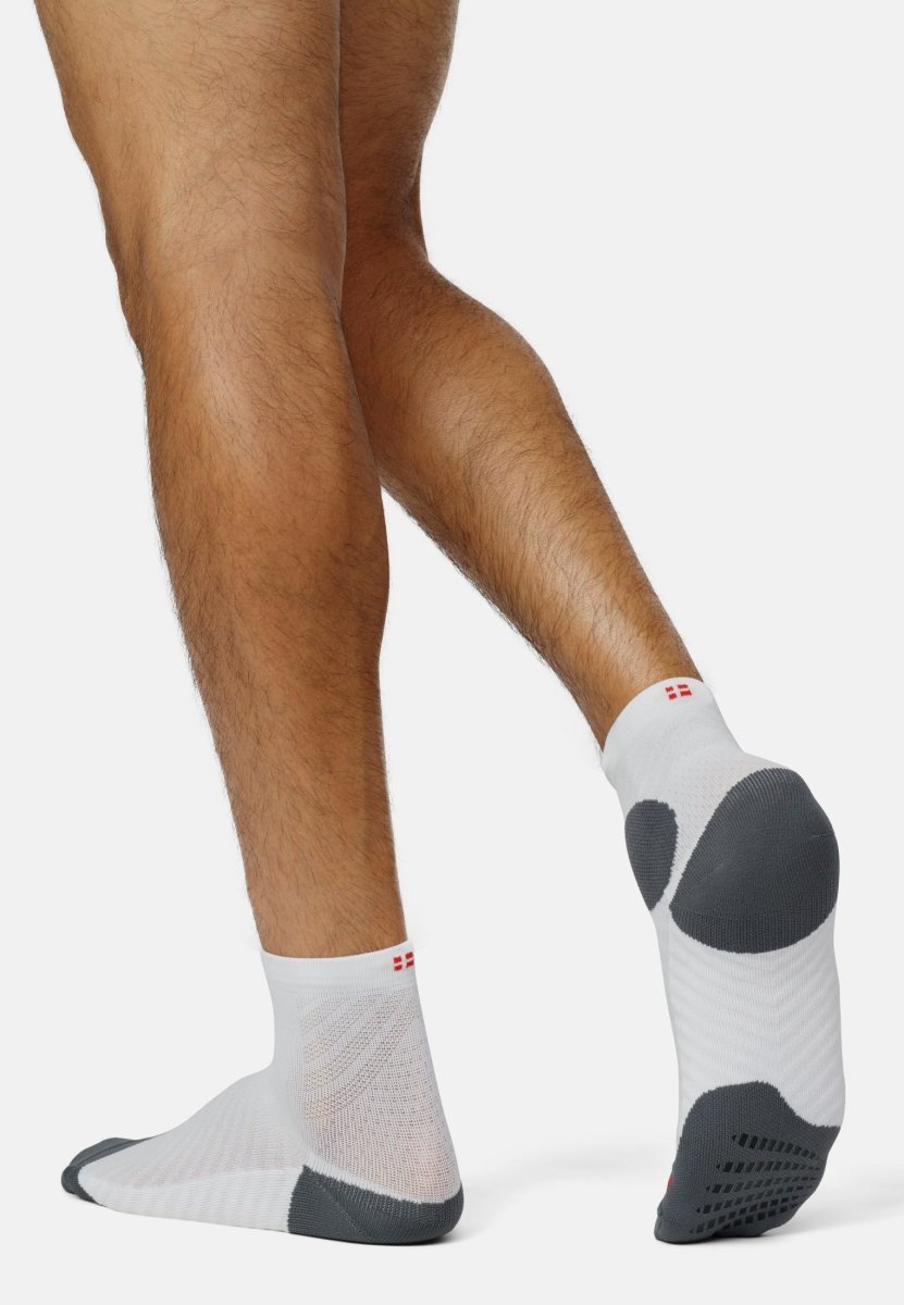 Person wearing white and gray anti-slip running socks with grip pads on a white background.