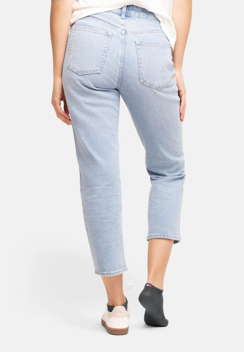 Person in light jeans wearing one beige sneaker and one dark gray bamboo low-cut sock.