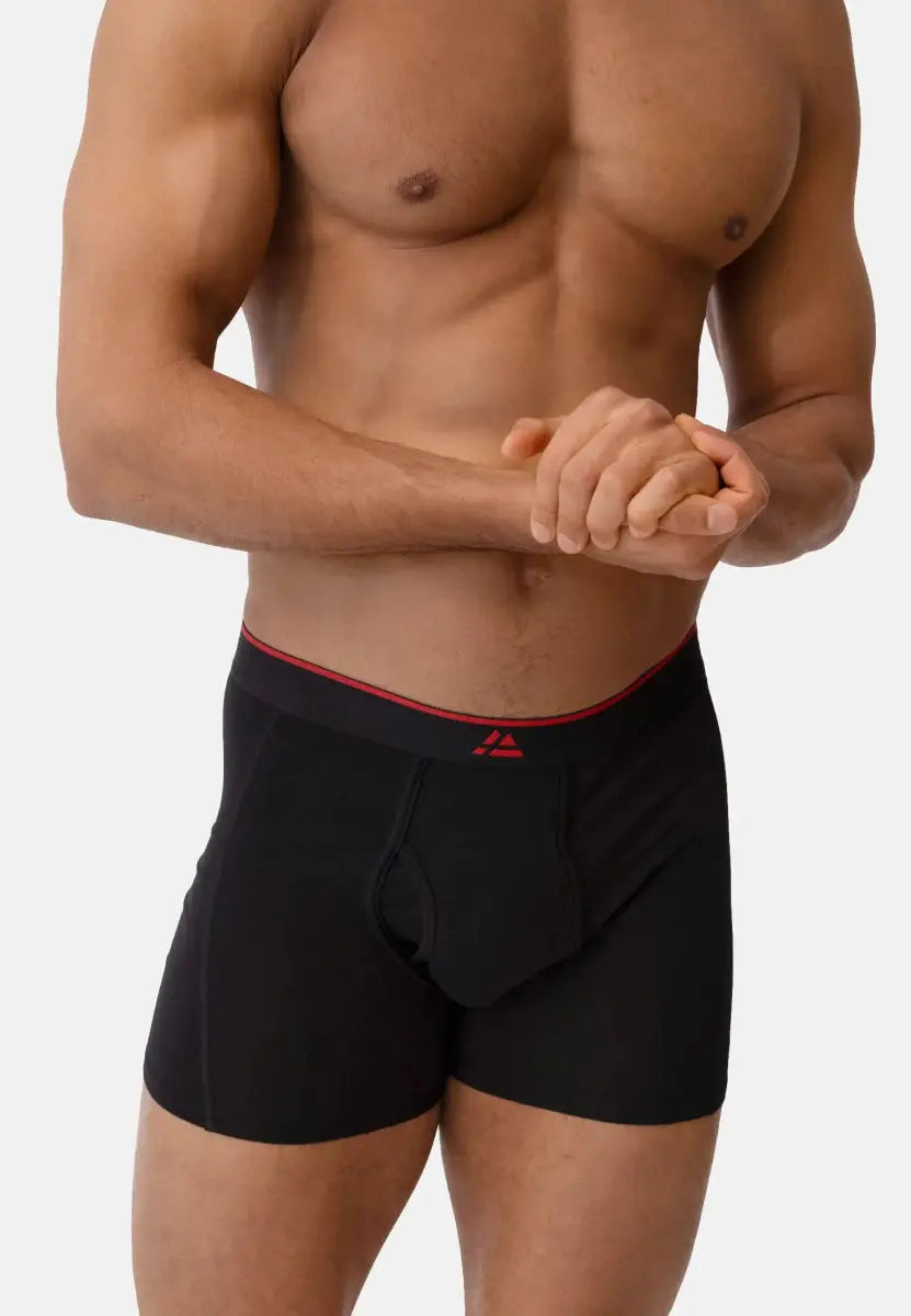Man wearing black bamboo trunks with red waistband and fly front, showing upper body and hands.