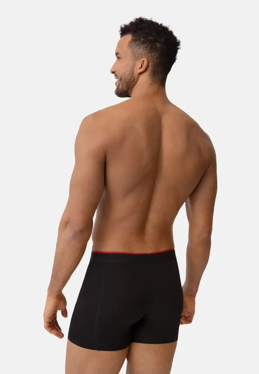 Man wearing black bamboo trunks with a red waistband, shown from the back, on a plain background.