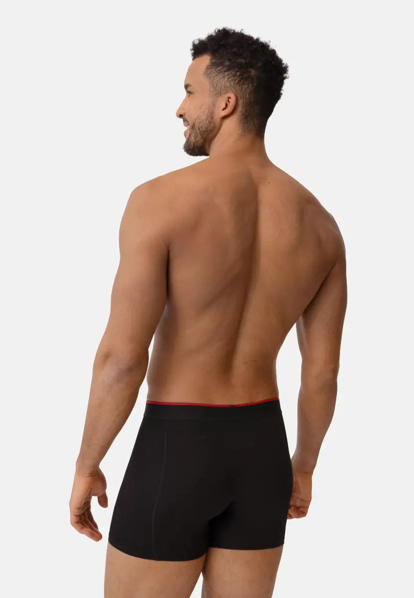 Man wearing black bamboo trunks with red waistband, viewed from behind.