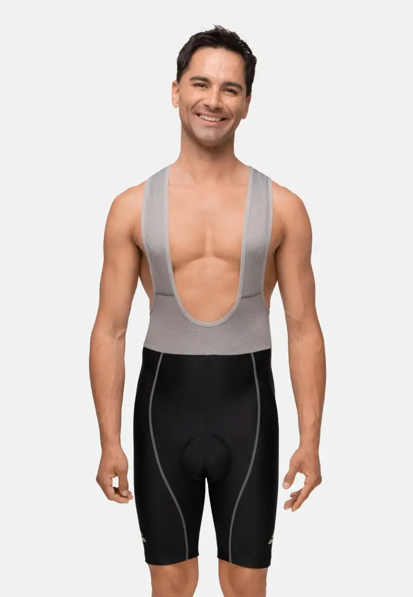Man wearing gray and black cycling bib shorts, smiling against a plain background.