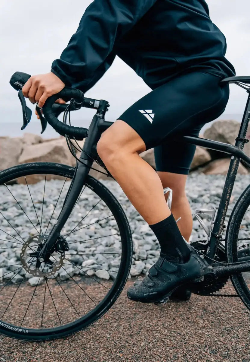 Cyclist in padded bike shorts riding on gravel path near rocks.