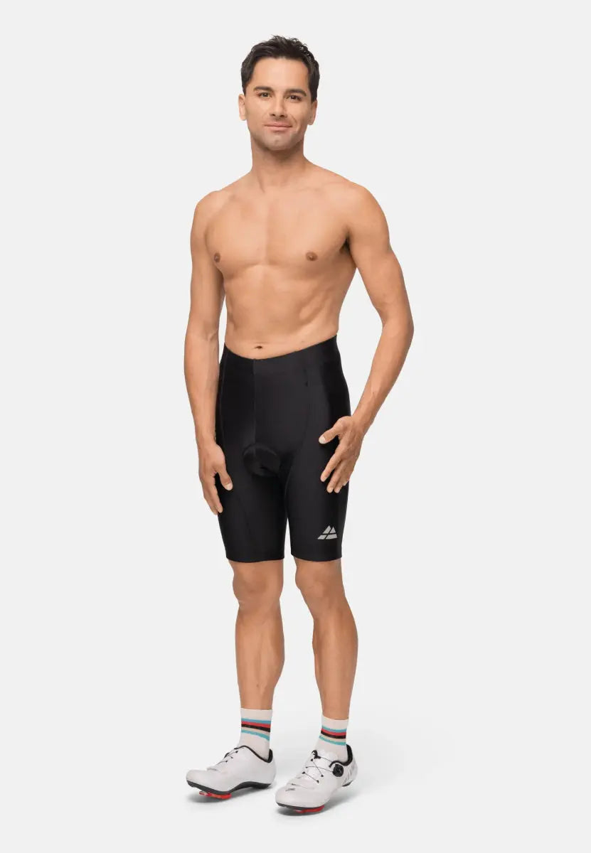 Man wearing black padded bike shorts, white cycling shoes, and striped socks, standing confidently.