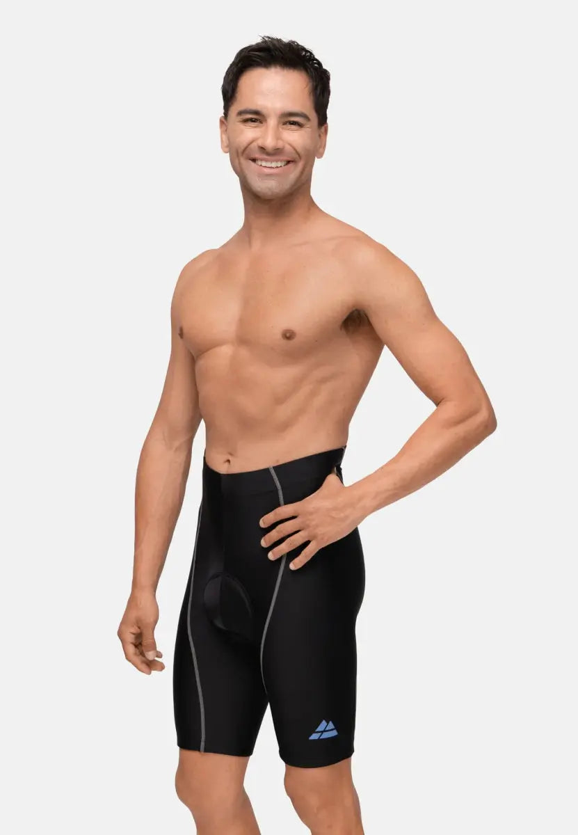 Shirtless man wearing black padded bike shorts with gray seams and a blue logo, smiling.