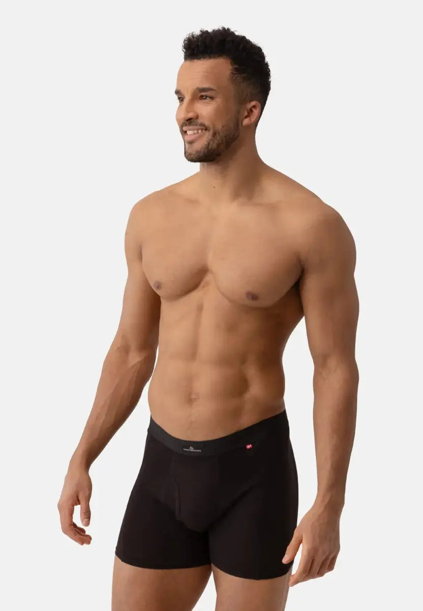 A person wearing black classic trunks with a fly, showcasing fit and style on a light background.