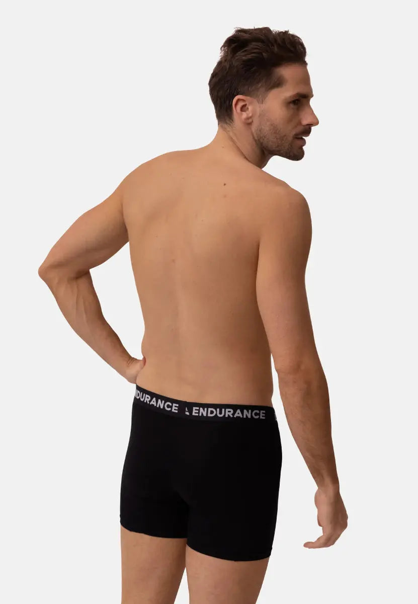 Man wearing black trunks with "ENDURANCE" waistband, viewed from behind.