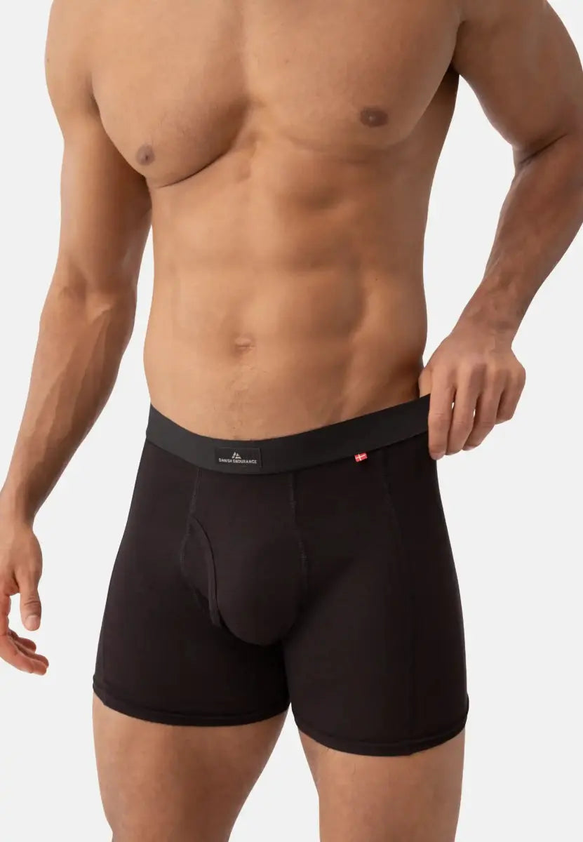 Man wearing black trunks with fly and logo waistband, showing fit and style.