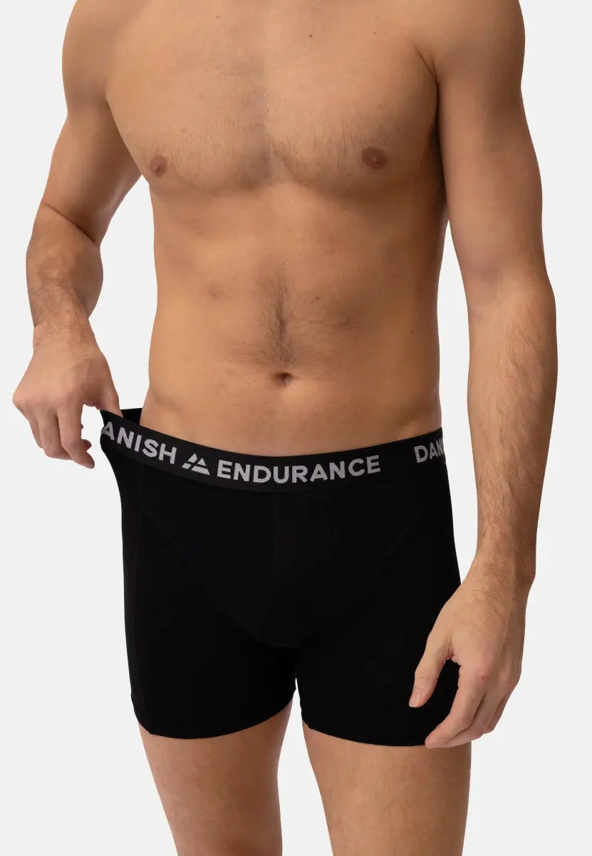 Person wearing black trunks with "DANISH ENDURANCE" waistband, adjusting the fit.