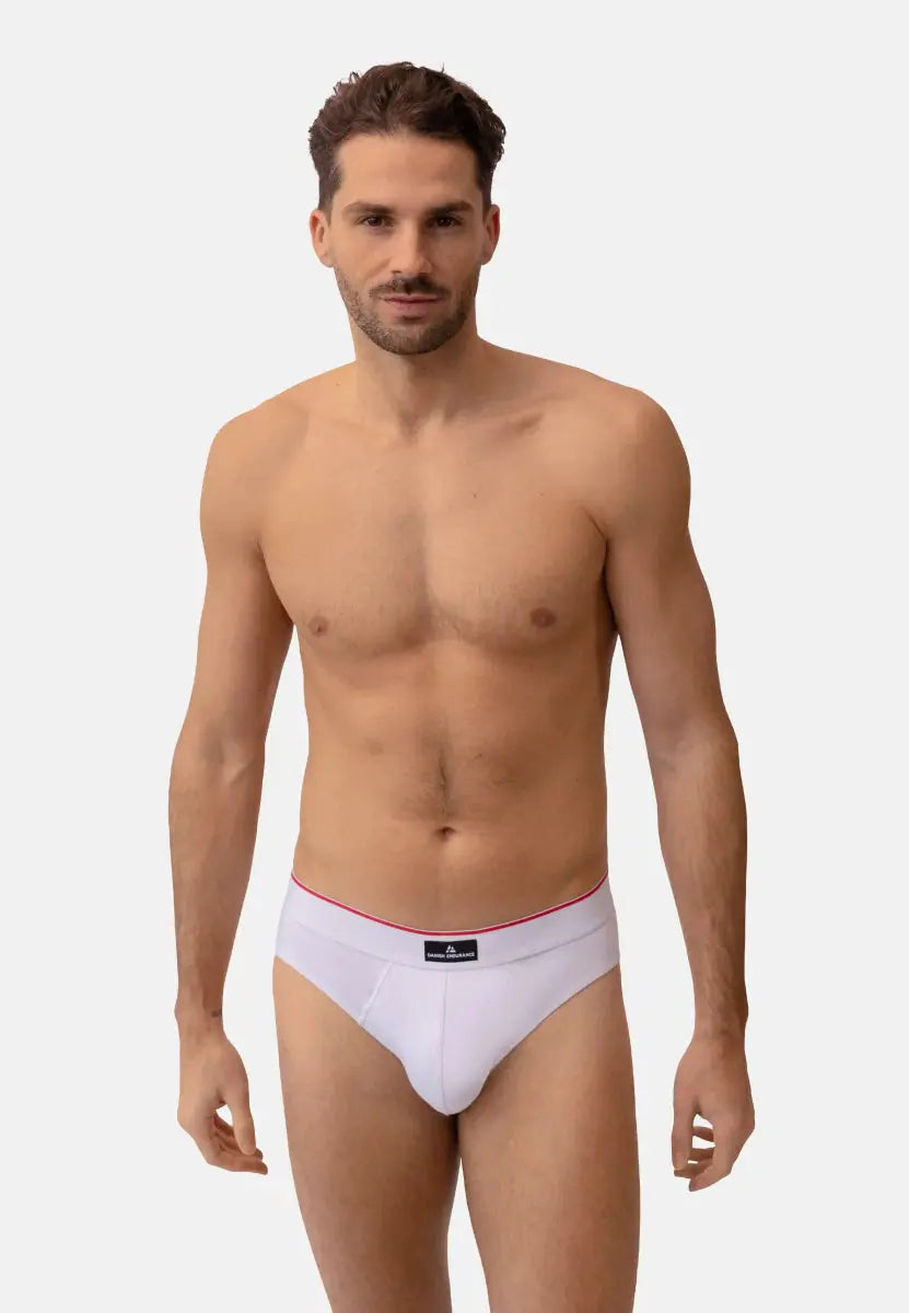 Man wearing white cotton briefs with red waistband accent, standing against a plain background.