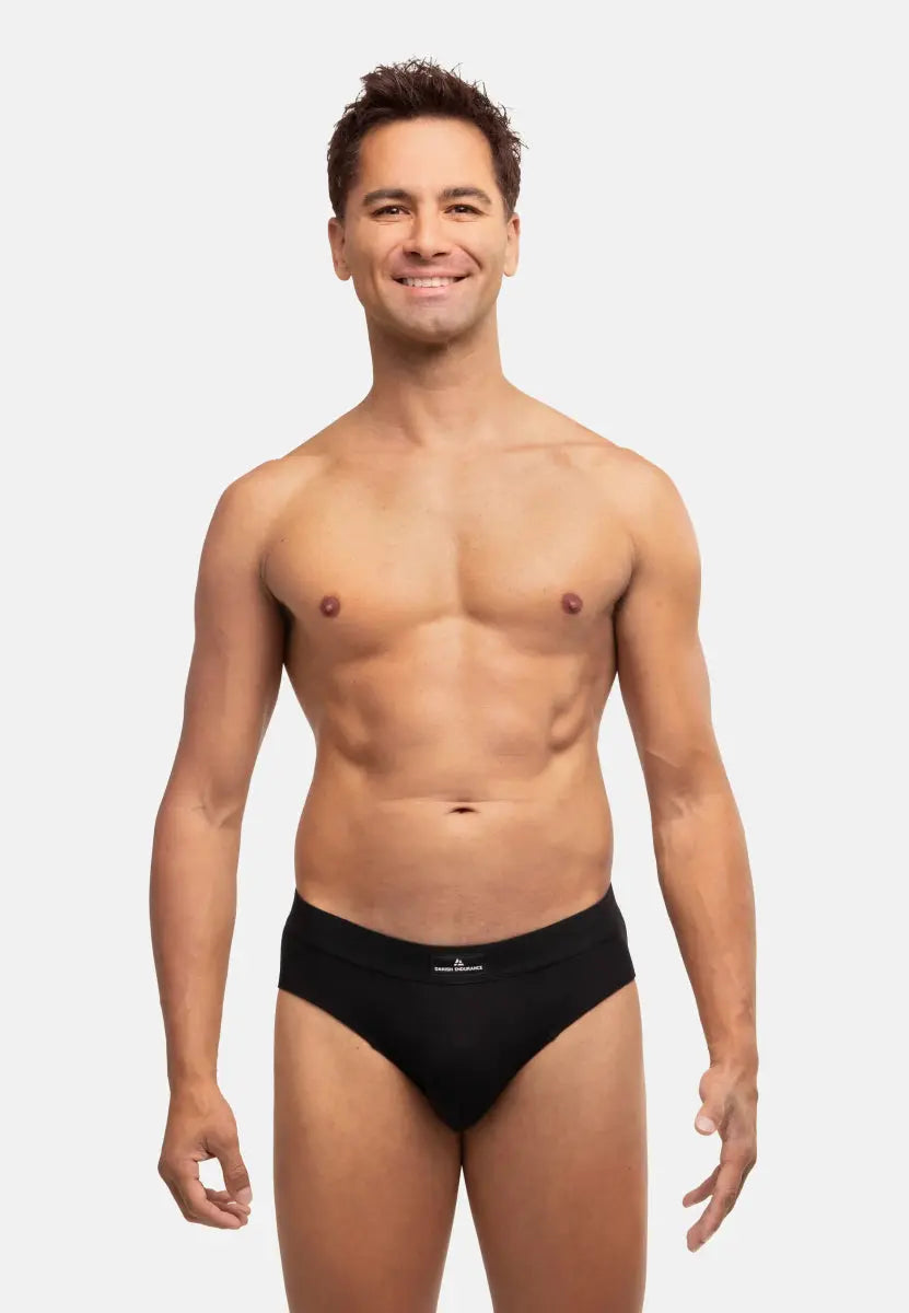 Person wearing black cotton briefs, standing, showcasing fit and style against a plain background.