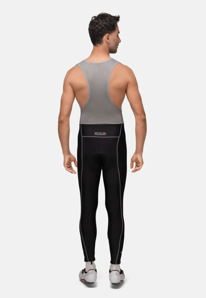 Man wearing black cycling bib pants with grey mesh top, "Danish Endurance" logo visible on back.