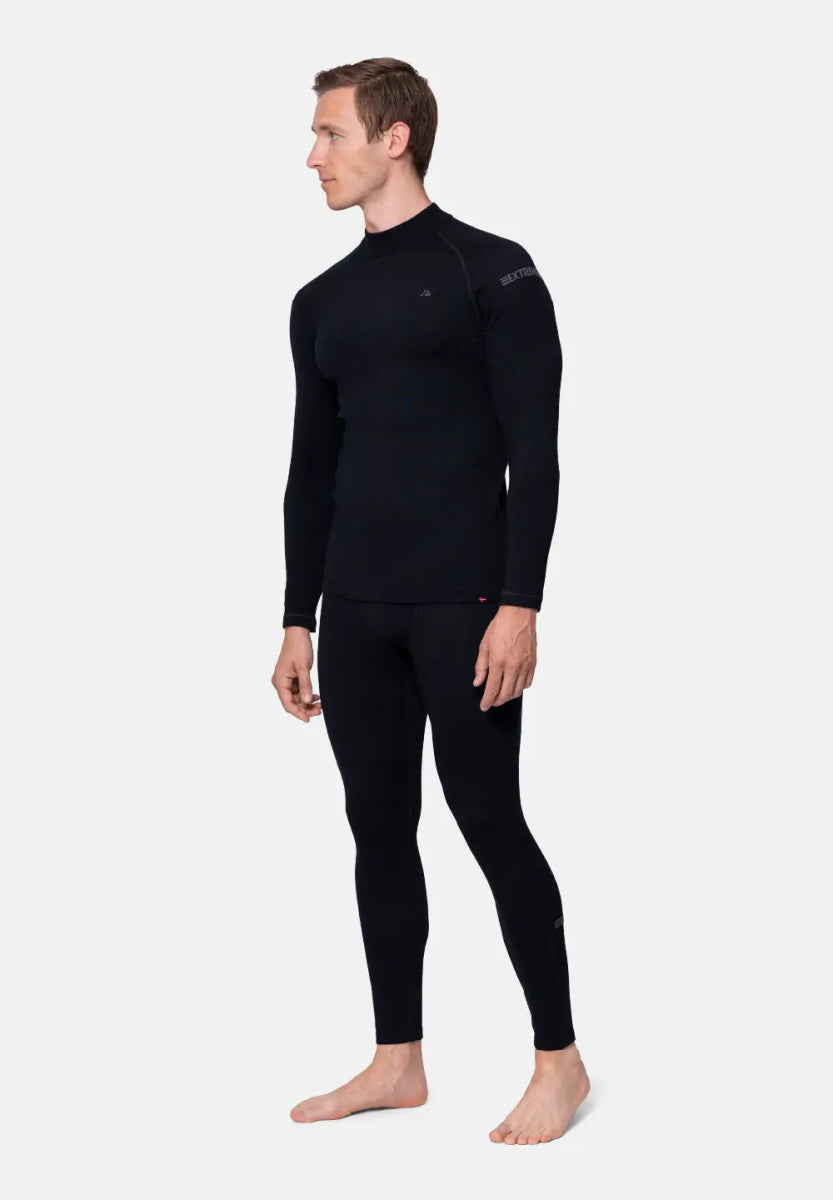 Man in black merino wool base layer set, long-sleeve top and leggings, on white background.