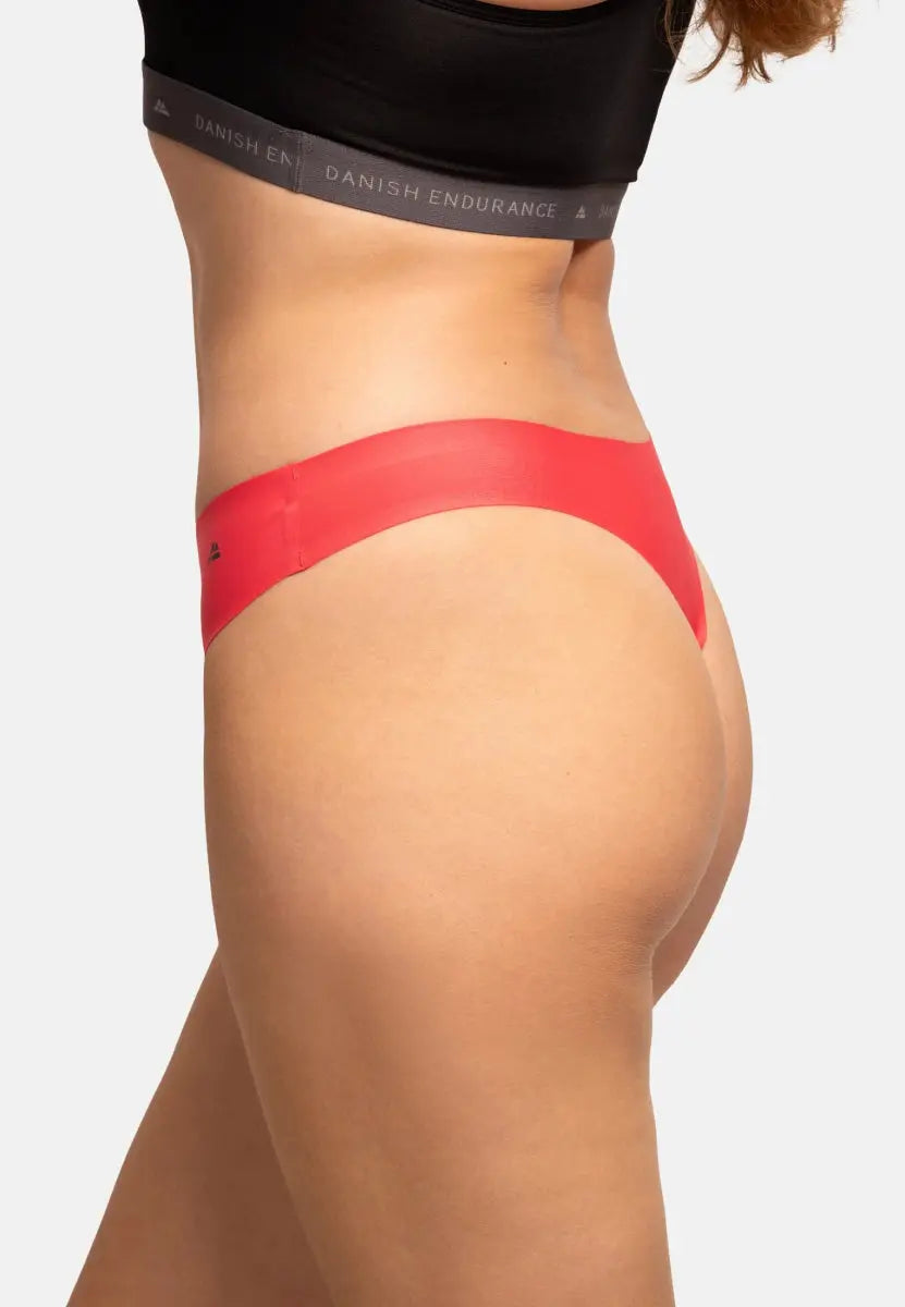 Red thong panties worn by a person, showing a seamless fit and black waistband detail.
