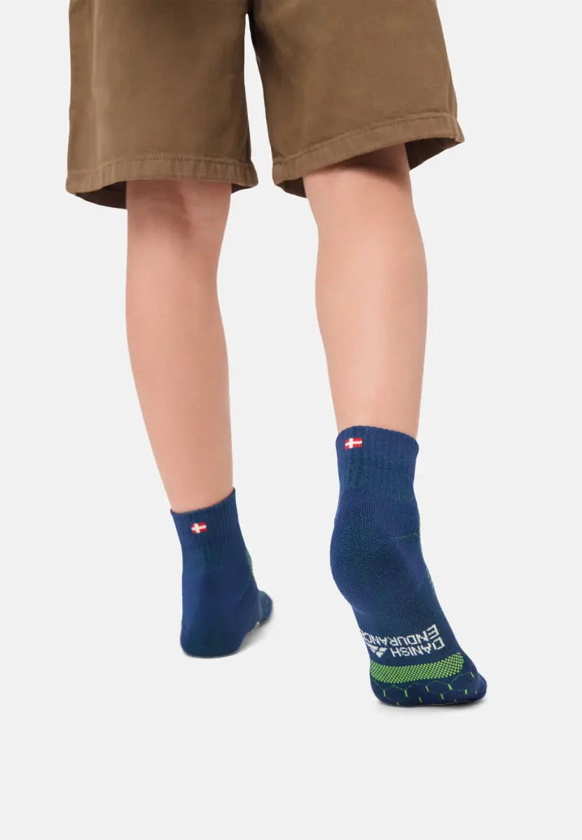 Child wearing blue padded running socks with a flag design, standing on a white background.