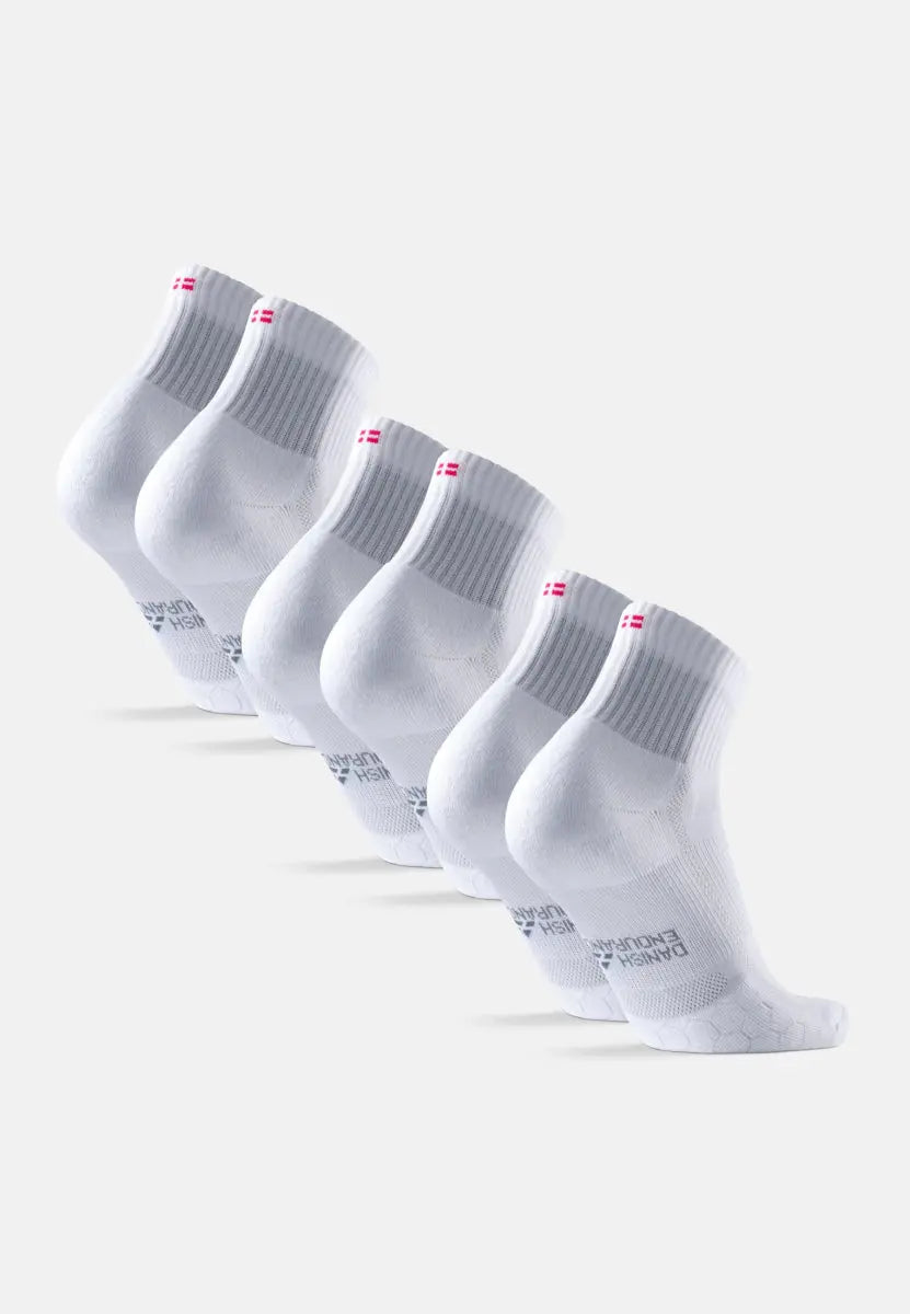 Five white kids' running socks with ribbed cuffs and extra heel padding, arranged in a row.