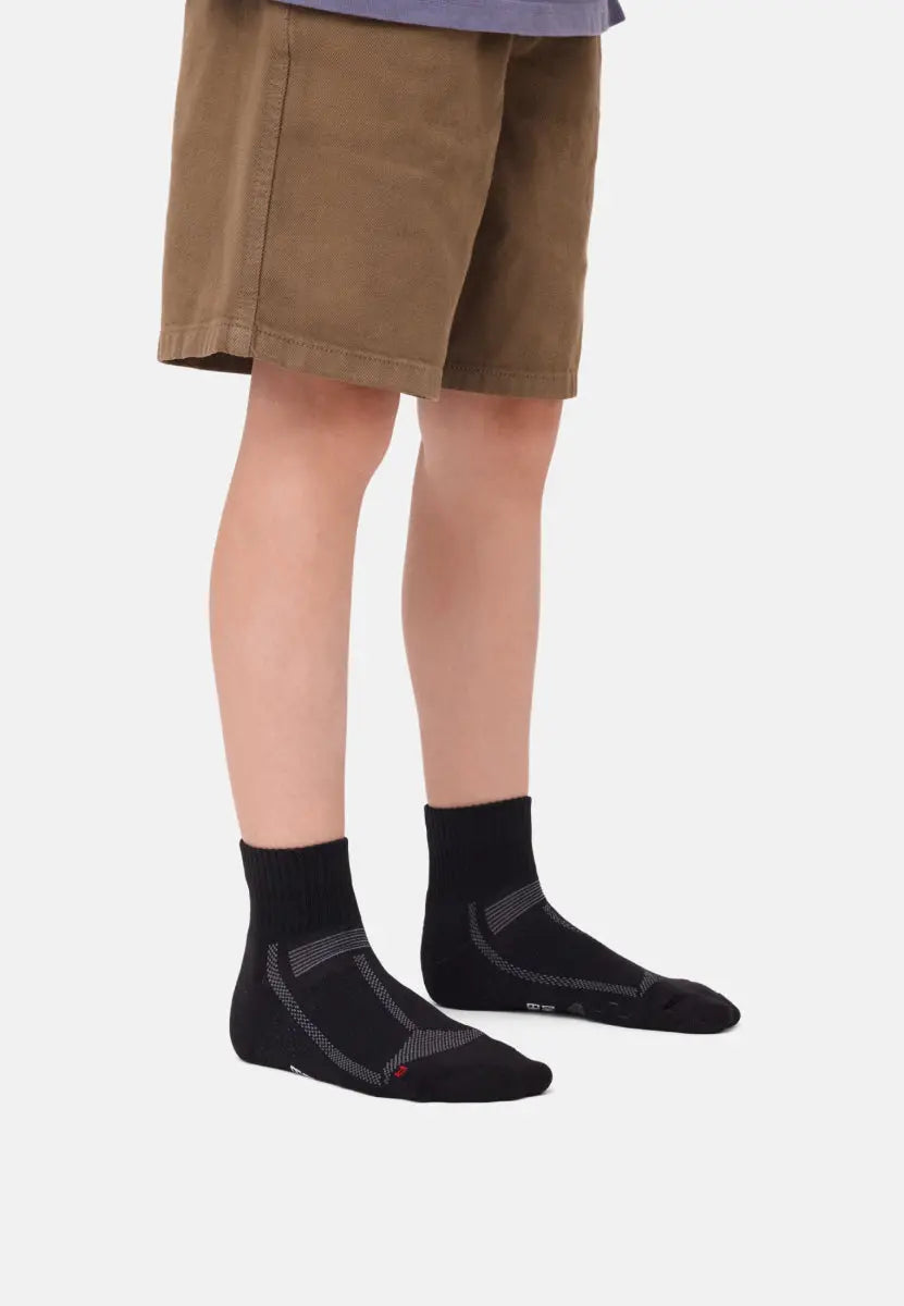 Child wearing black padded running socks and brown shorts against a plain background.
