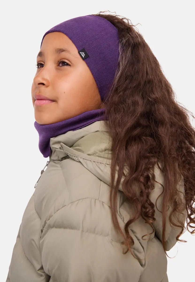 Child wearing a purple merino headband and beige puffer jacket, looking to the side.