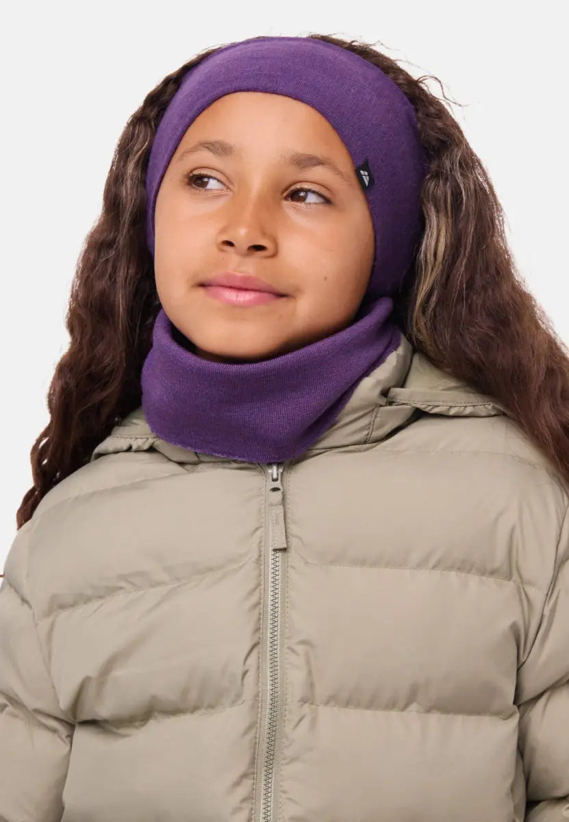 Child in purple merino headband and scarf, wearing a beige puffer jacket, looking to the side.