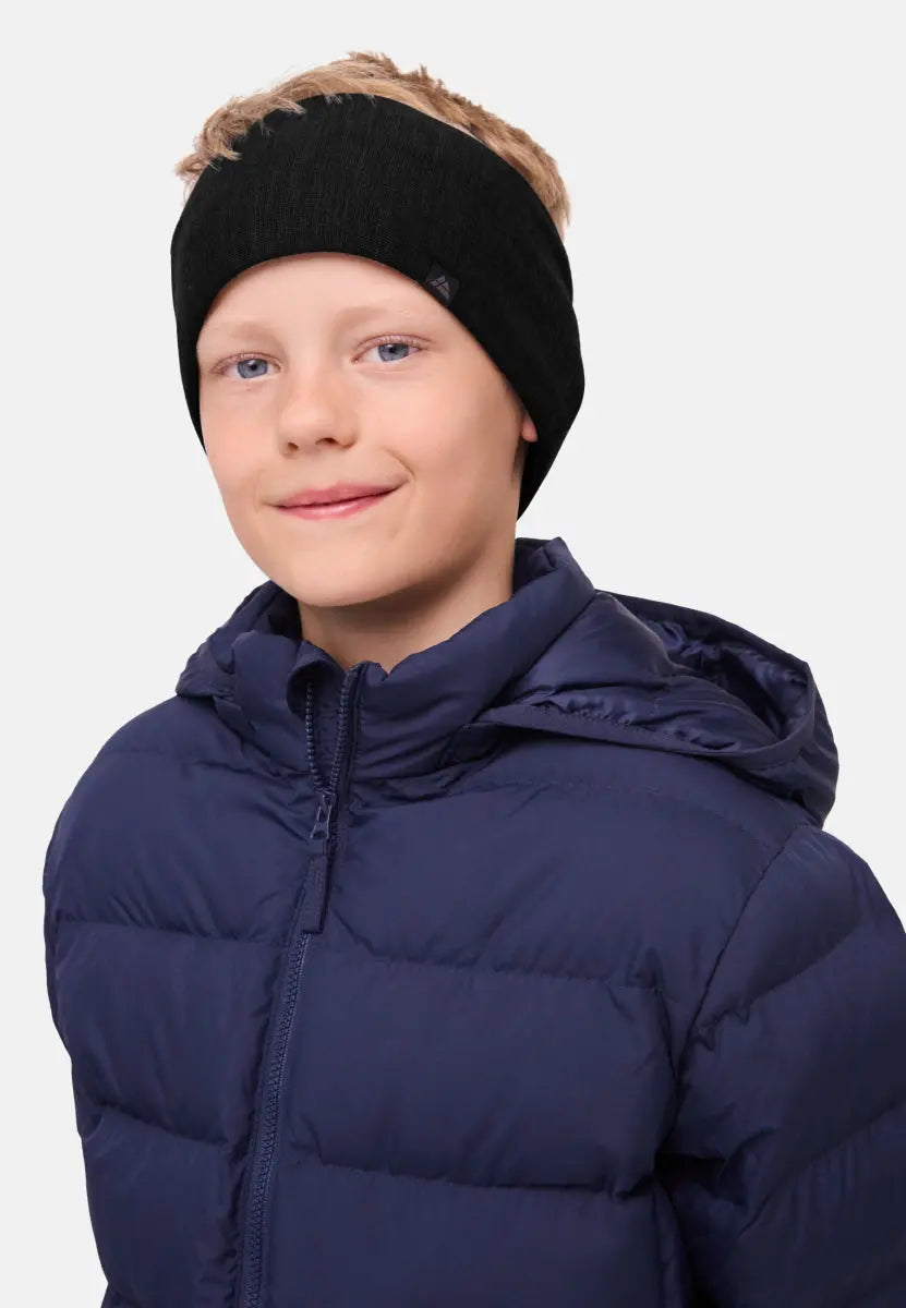 Child wearing a black merino headband and navy puffer jacket, smiling gently.
