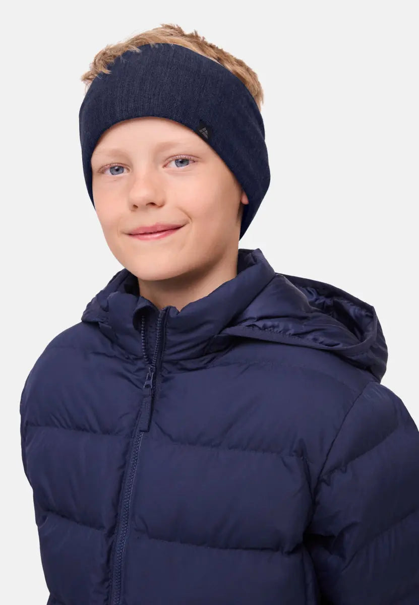 Child wearing a navy merino headband and matching puffer jacket, smiling slightly.
