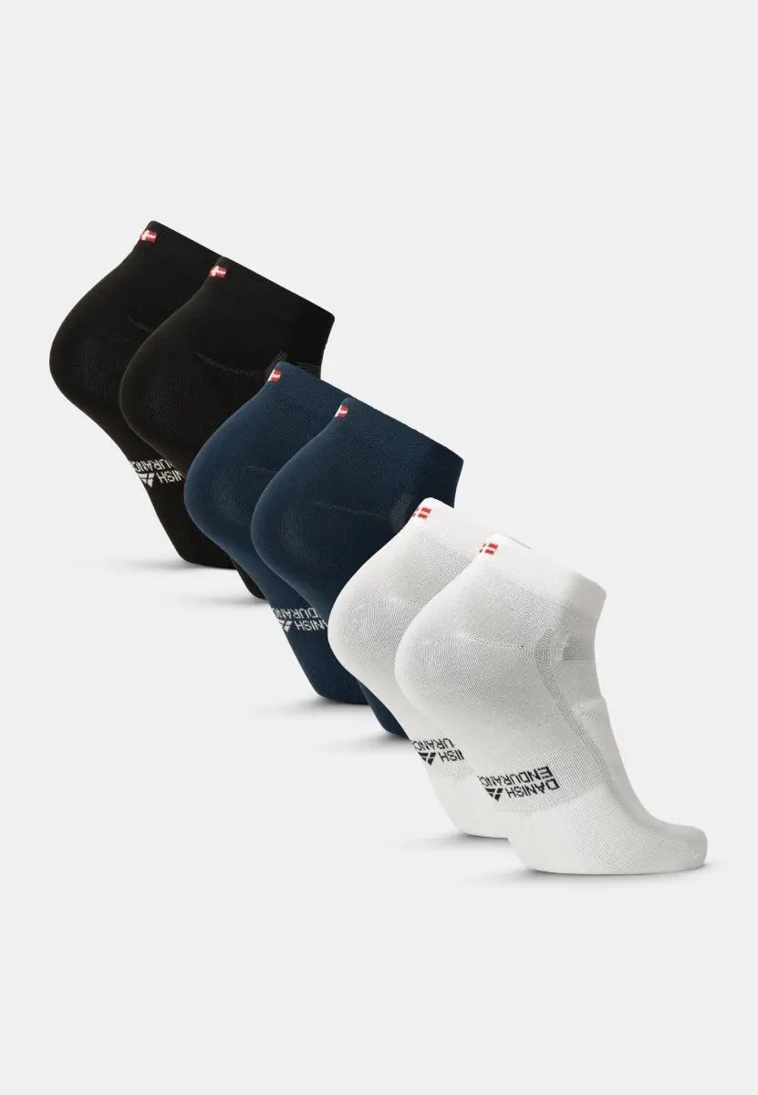 Five pairs of low-cut cycling socks in black, navy, and white, displayed in a row.