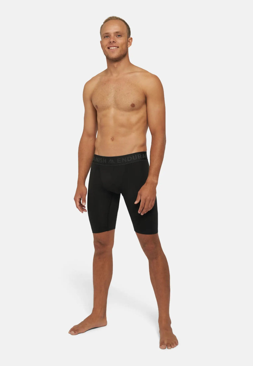 Man wearing black compression shorts, standing barefoot against a plain white background.