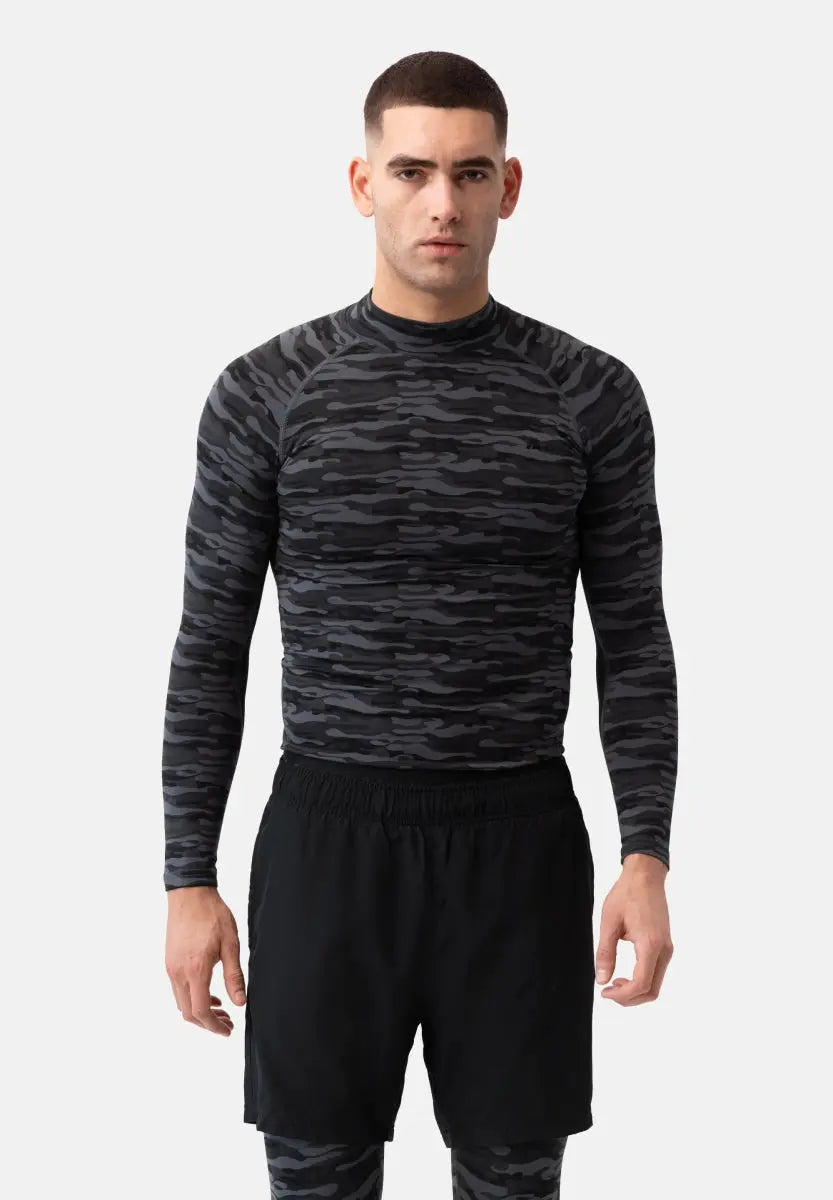 Man wearing a dark camo long-sleeve compression shirt and black shorts, facing forward.