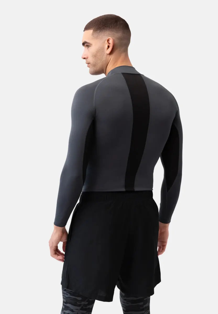 Man in gray long sleeve compression shirt with black stripe, black shorts, and patterned leggings.