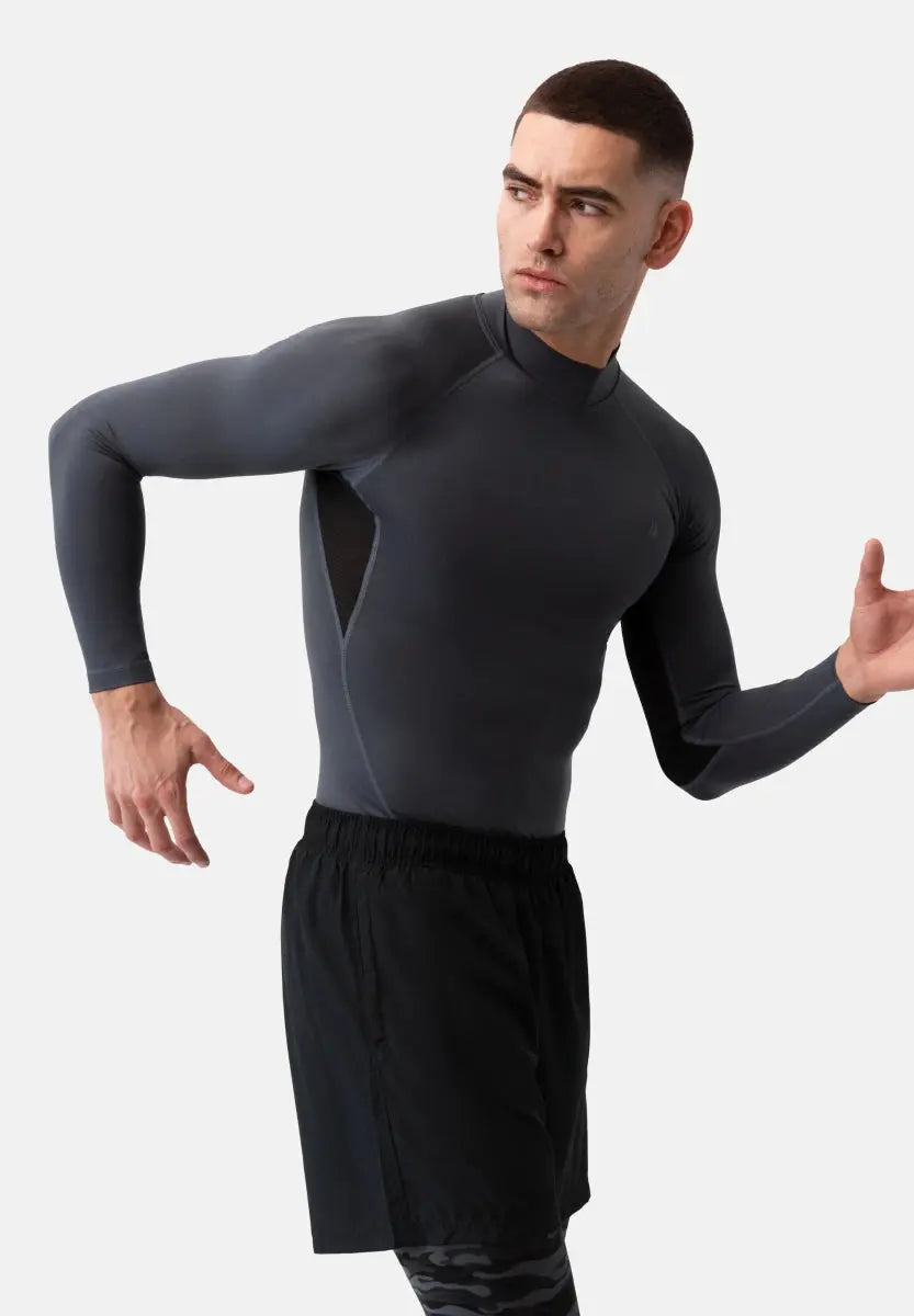 Person in dark gray compression shirt and black shorts, posing with arms bent, looking to the side.