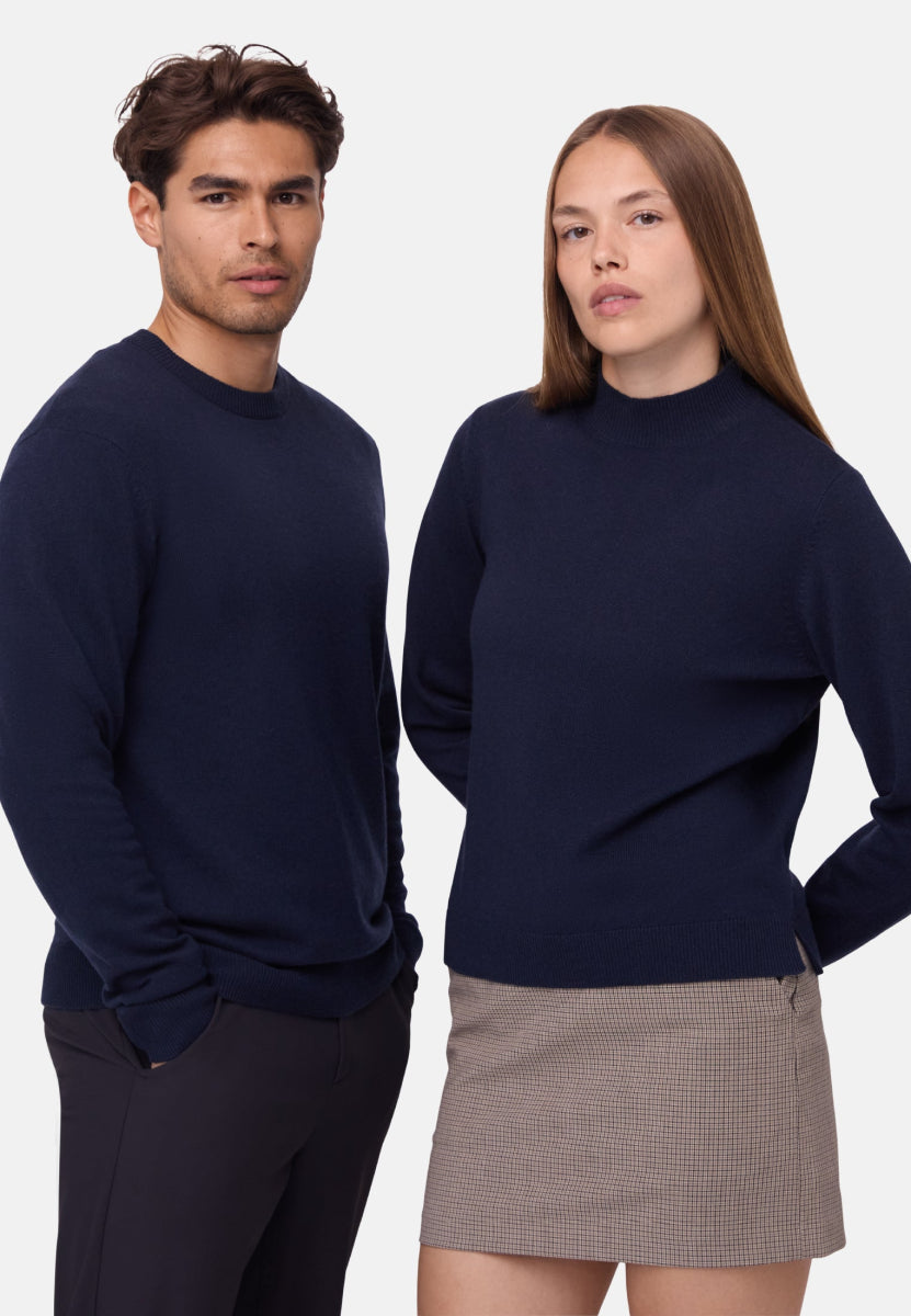 Two models in navy sweaters; man in dark pants, woman in plaid skirt, against a white background.