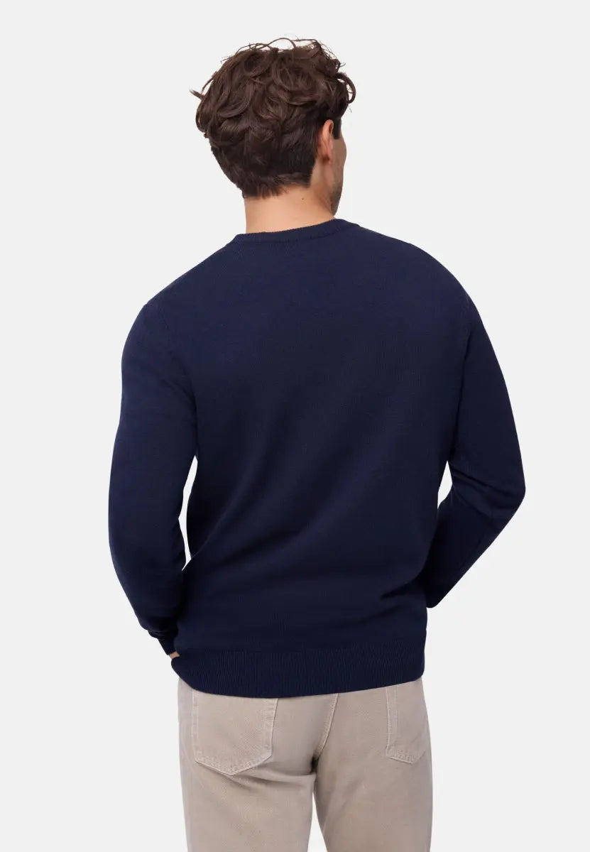 Back view of a man in a navy blue Merino cashmere sweater and beige pants.