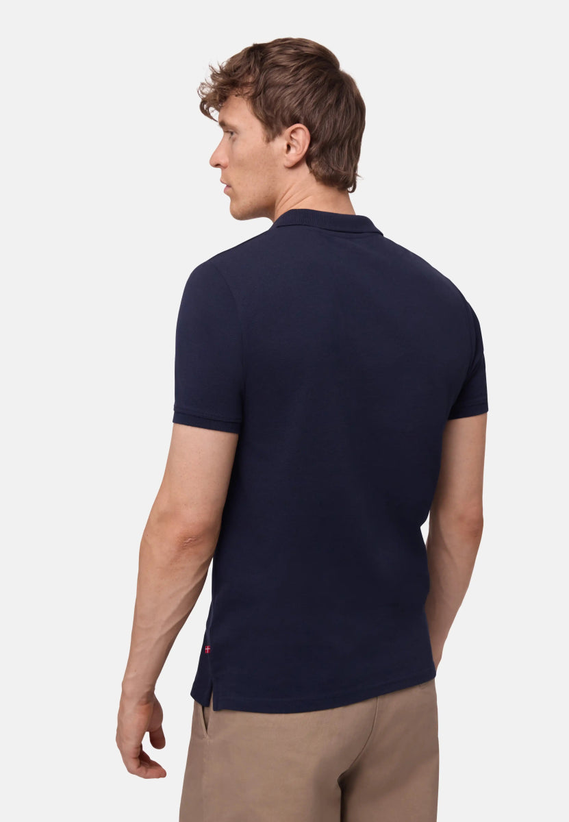 Man wearing a navy polo shirt with short sleeves and beige pants, viewed from the back.