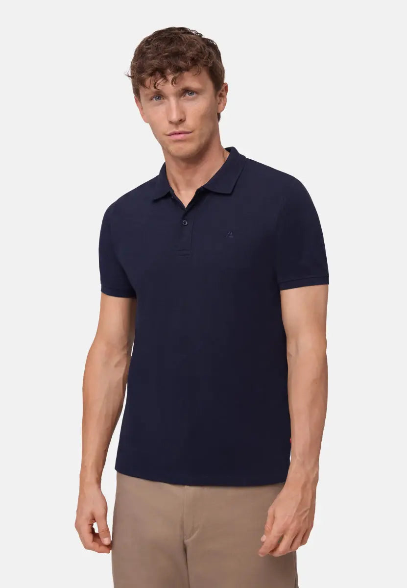 Man wearing a navy blue polo shirt with short sleeves and beige pants.