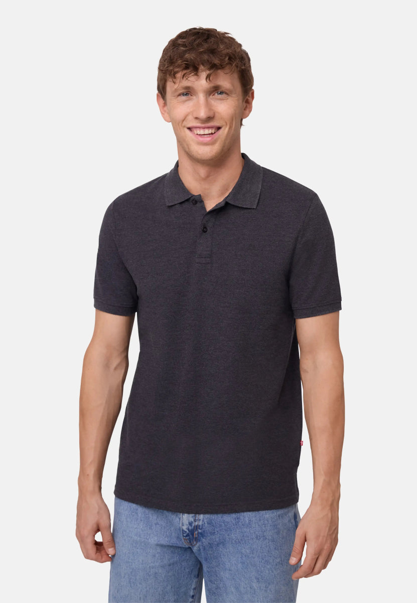 Man wearing a dark gray organic cotton polo shirt with blue jeans, smiling.