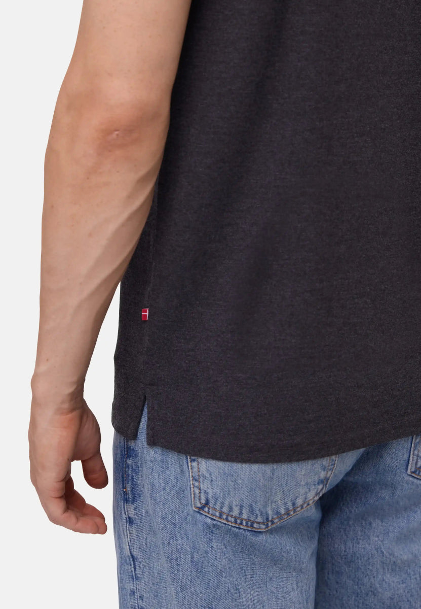 Close-up of a dark polo shirt with side seam detail, worn with light blue jeans.