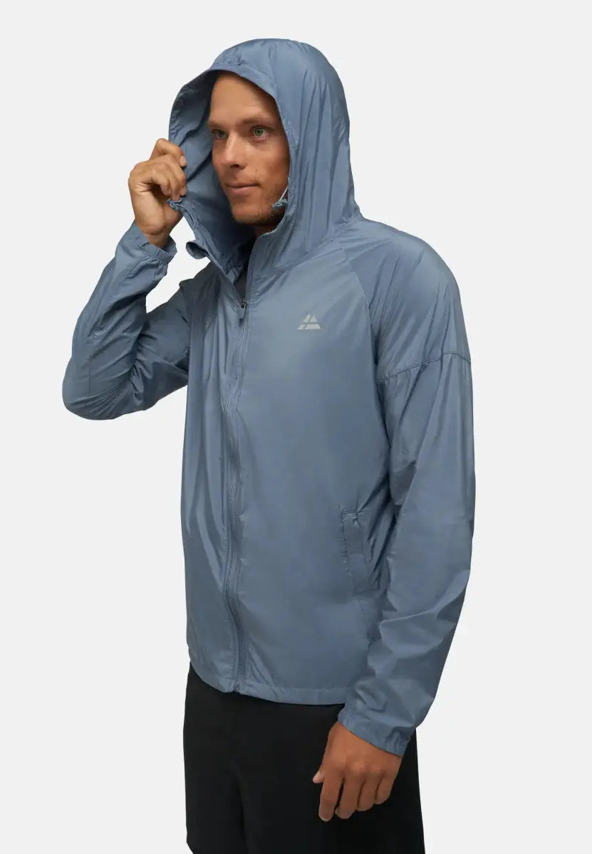 Man in light blue windbreaker jacket with hood up, adjusting it with his right hand.