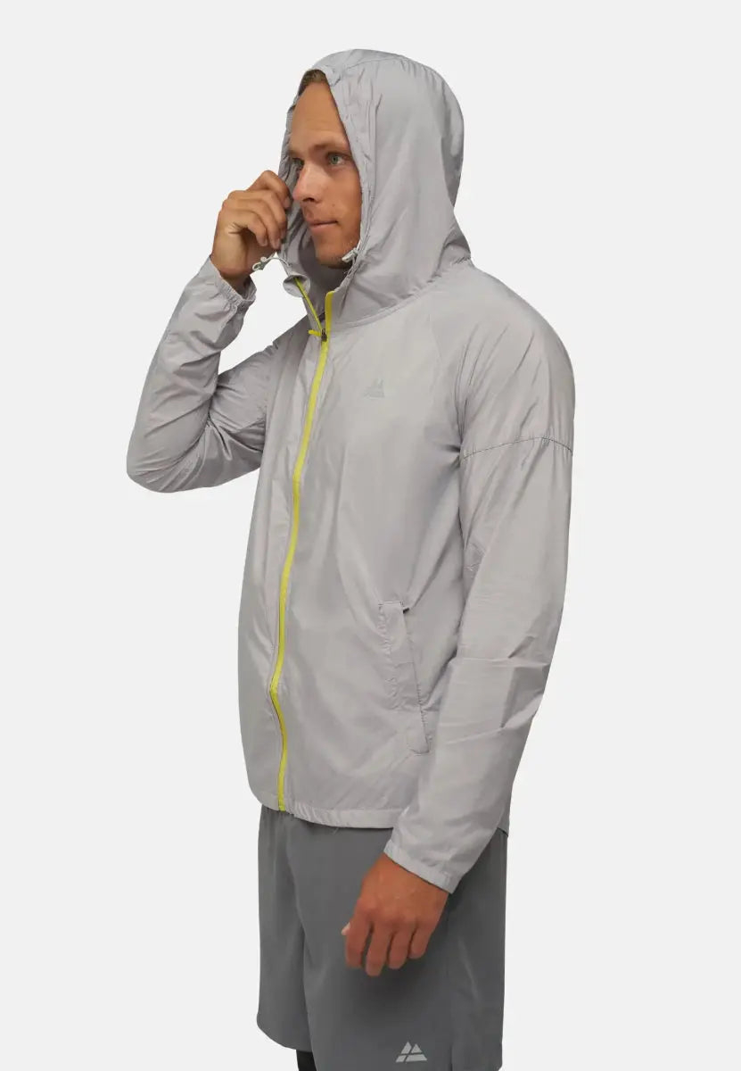 Man wearing a light gray hooded windbreaker jacket with yellow zipper, hands adjusting hood.