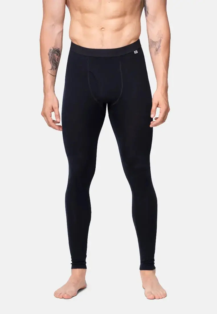 Man wearing black merino wool base layer pants with fly, showing front view from waist to feet.
