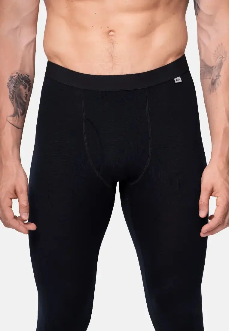 Man wearing black merino wool base layer pants with a fly, showcasing fit and waistband detail.