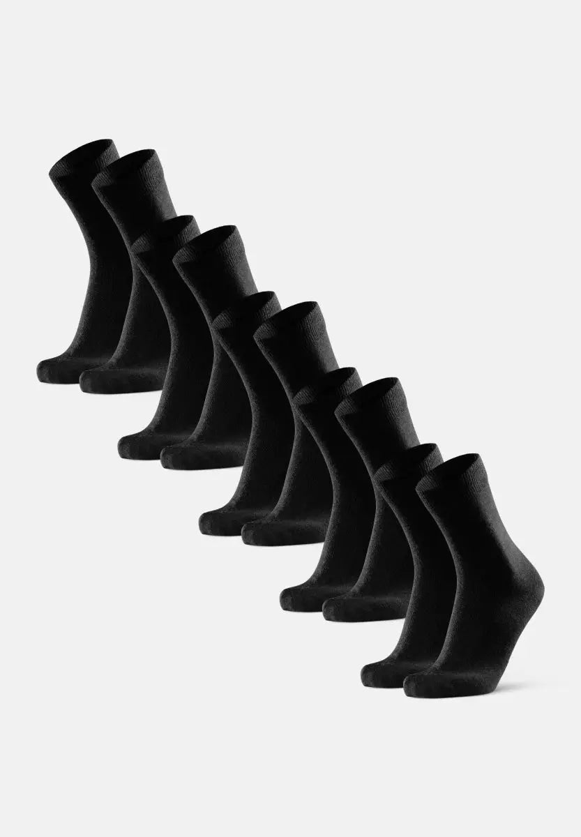 Eight black Merino wool dress socks arranged in a diagonal line on a white background.