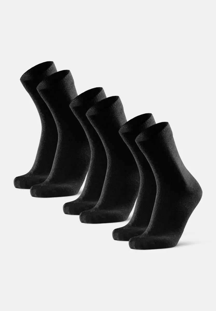 Six pairs of black merino wool dress socks standing upright on a white background.