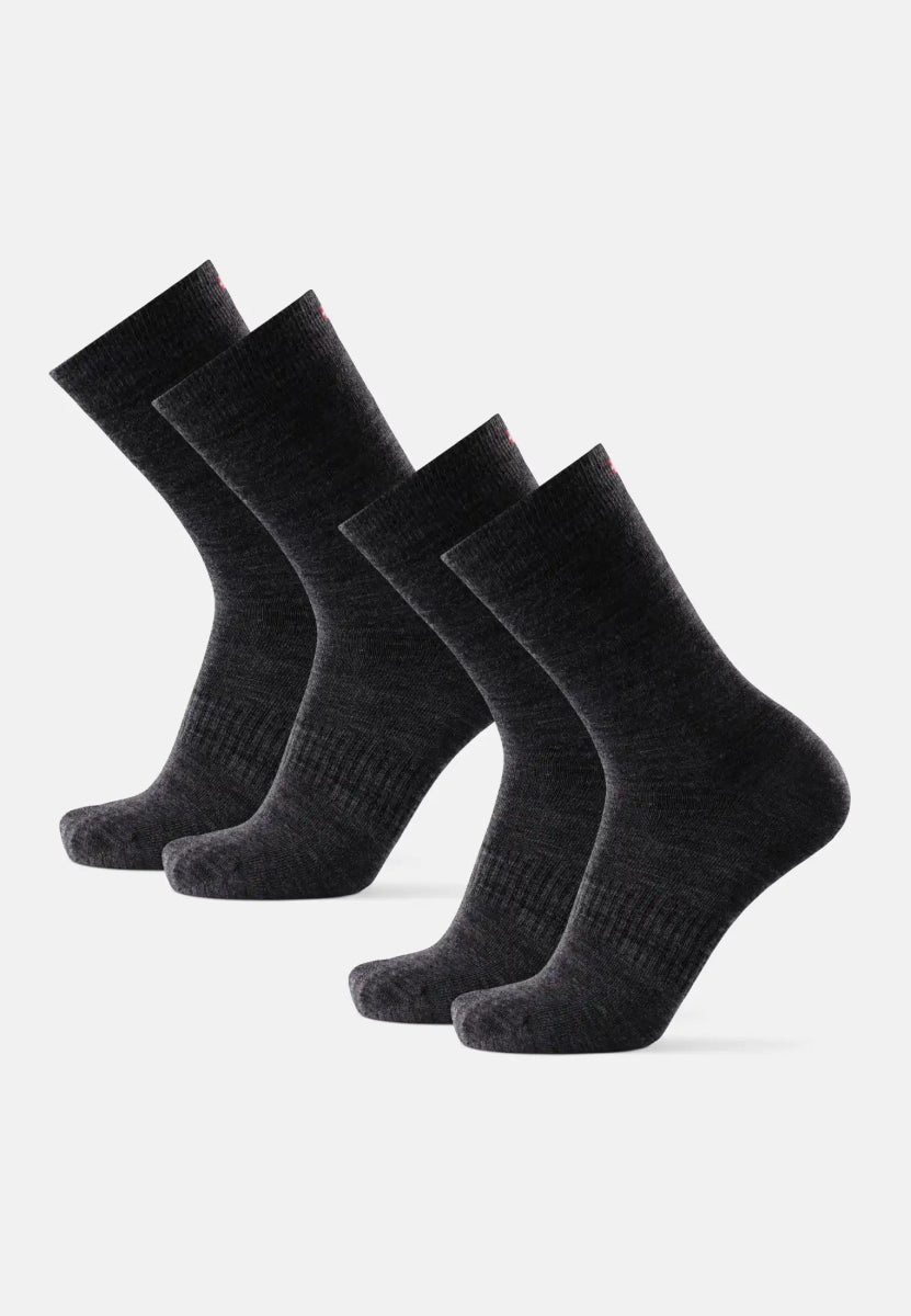 Four dark gray merino wool hiking liner socks standing upright, side by side.