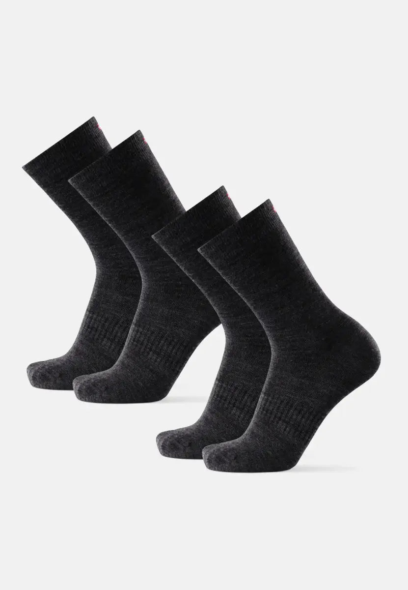 Four dark gray merino wool hiking liner socks standing upright, side by side.